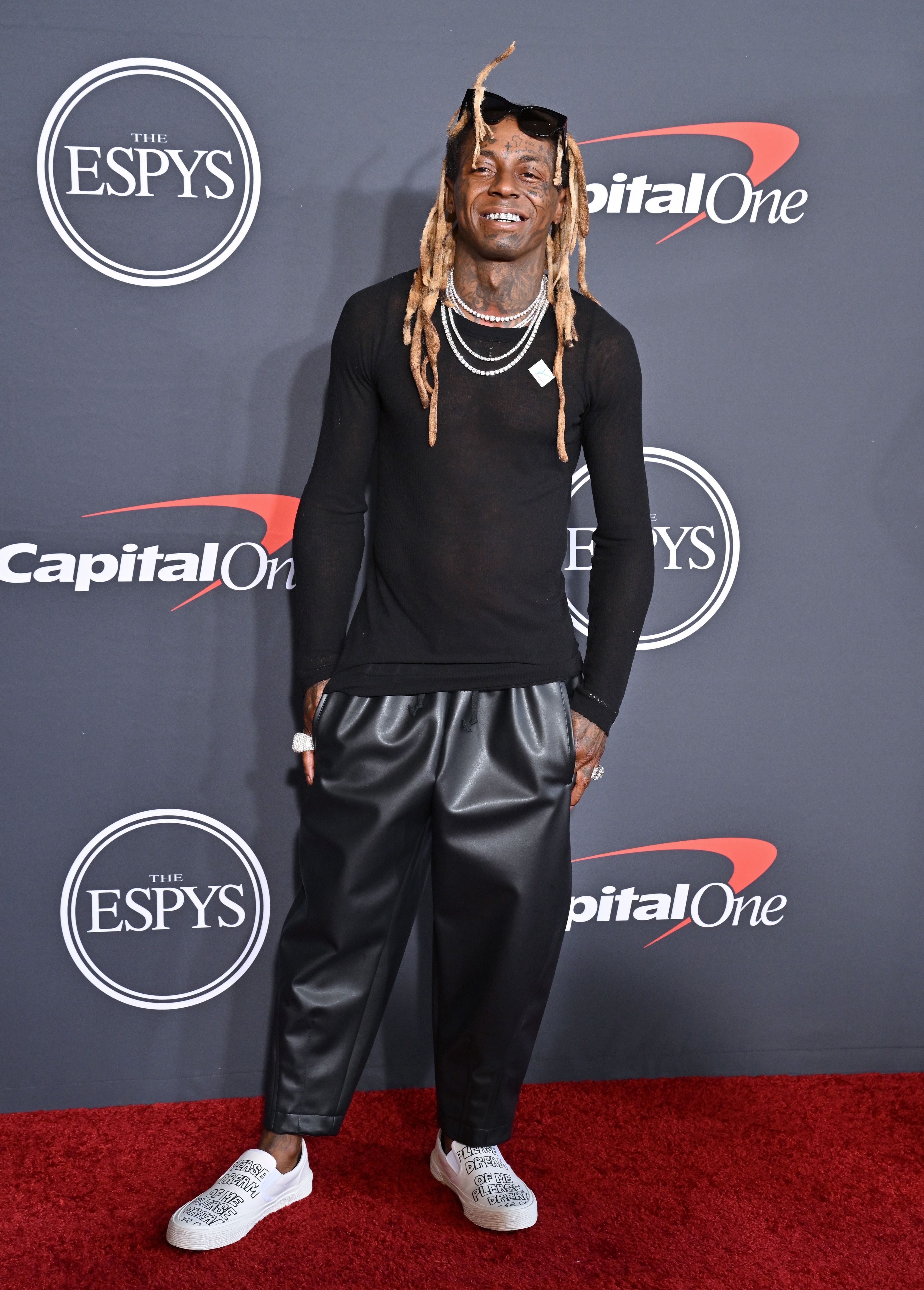 Person connected reddish carpet wearing a achromatic long-sleeve shirt, escaped achromatic pants, and achromatic sneakers, with agelong hairsbreadth styled successful locks