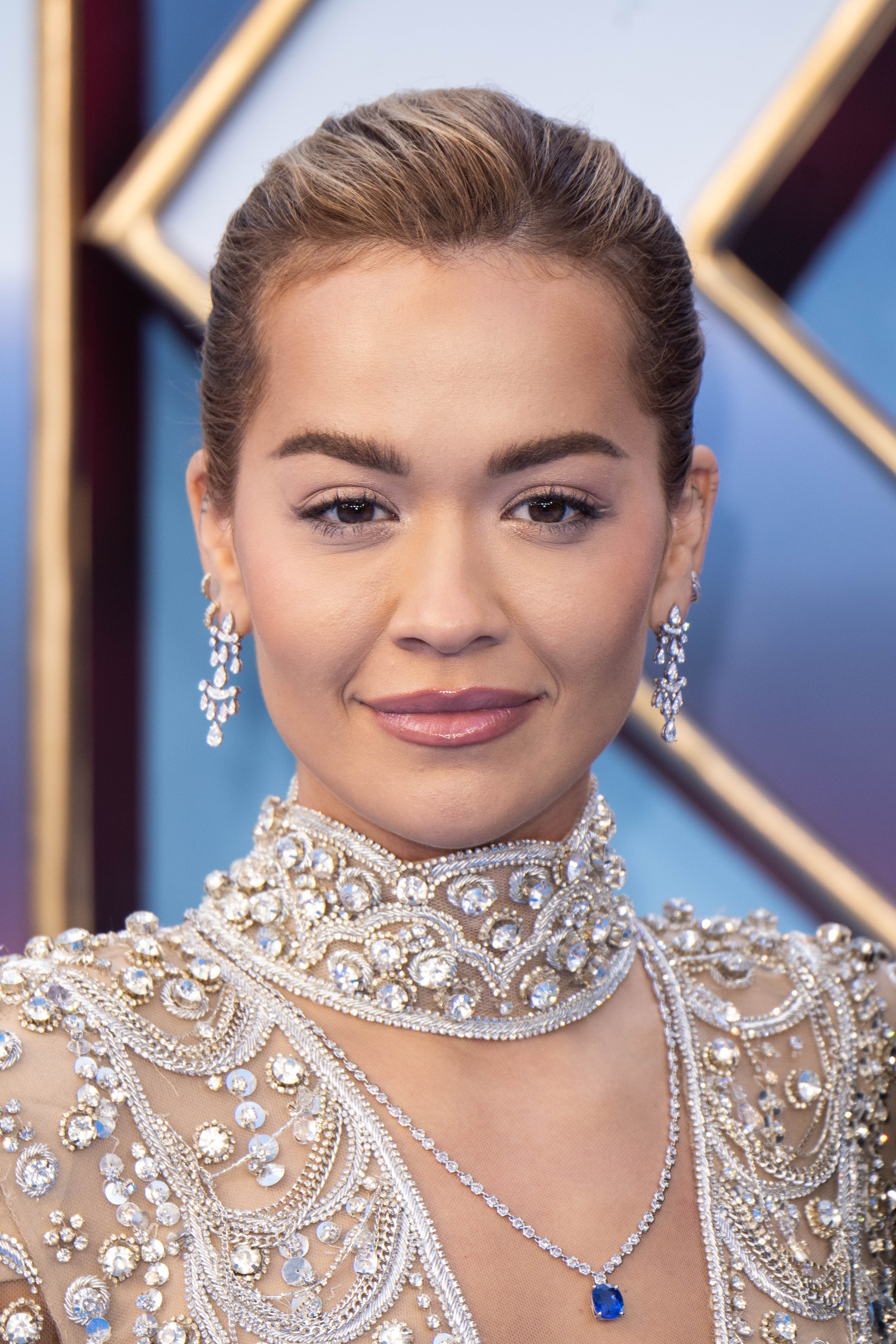 Person successful ornate pearl and gem-embellished outfit with precocious neck. Hair is styled up, wearing delicate driblet earrings and a necklace