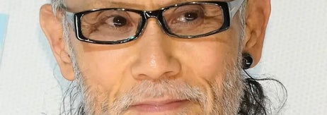 有名人がメガネをかけ、黒のスタイリッシュな服装を着ている。