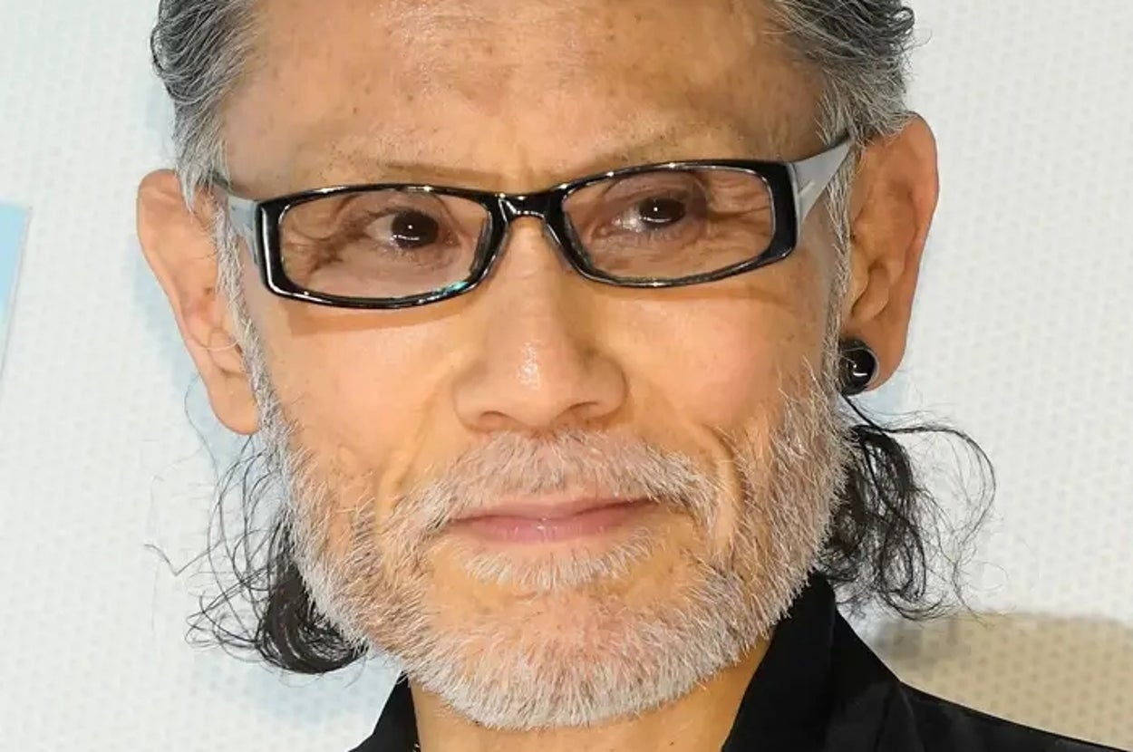 有名人がメガネをかけ、黒のスタイリッシュな服装を着ている。