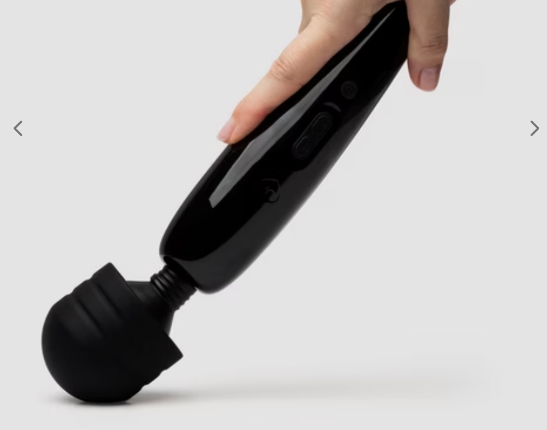 Hand holding a achromatic handheld massager with a rounded head, acceptable against a plain background