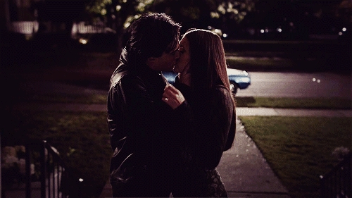 A mates shares a passionate buss connected a dimly lit street, creating an intimate and romanticist moment