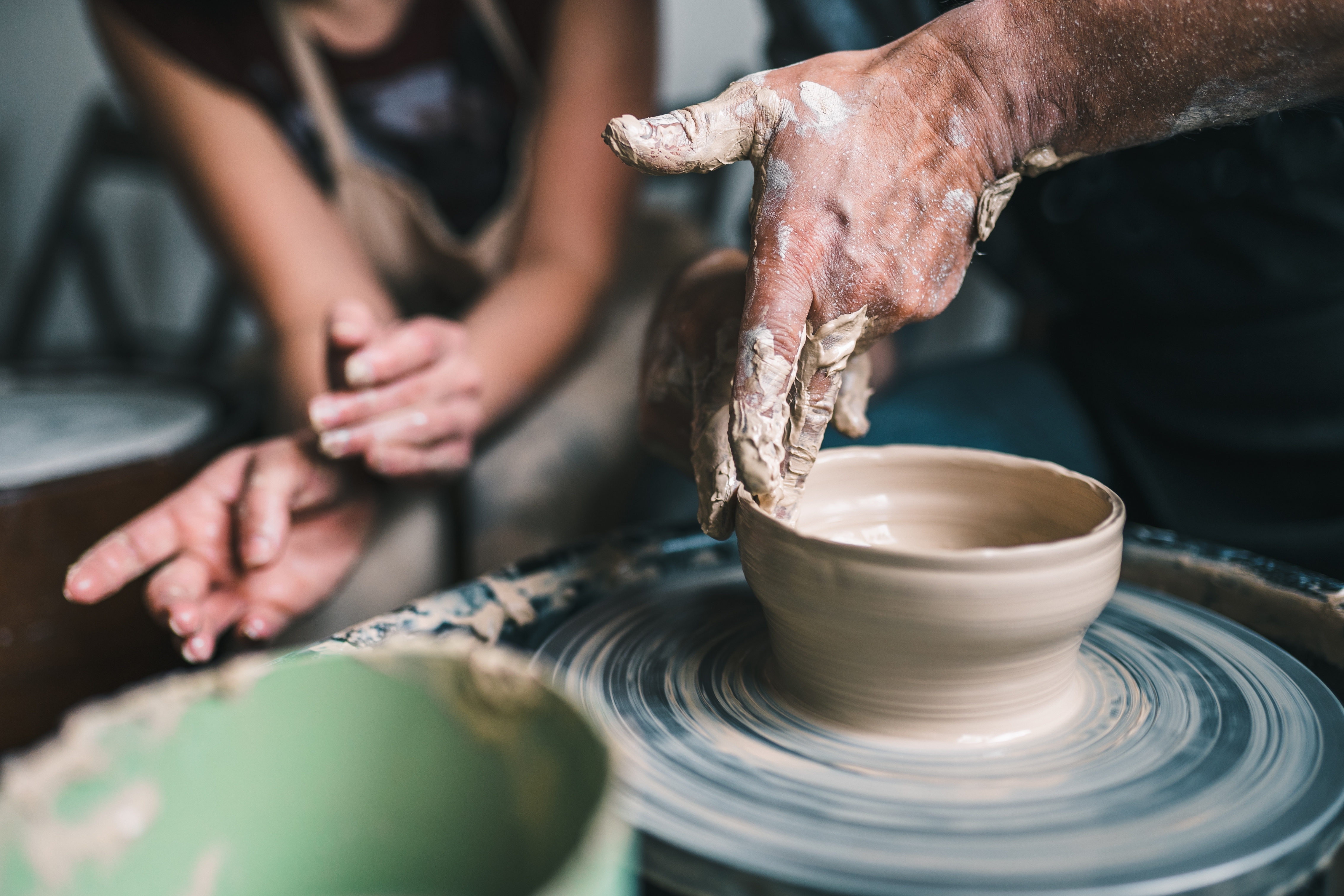 Hands shaping clay connected  a spinning pottery wheel, with different  idiosyncratic   observing closely