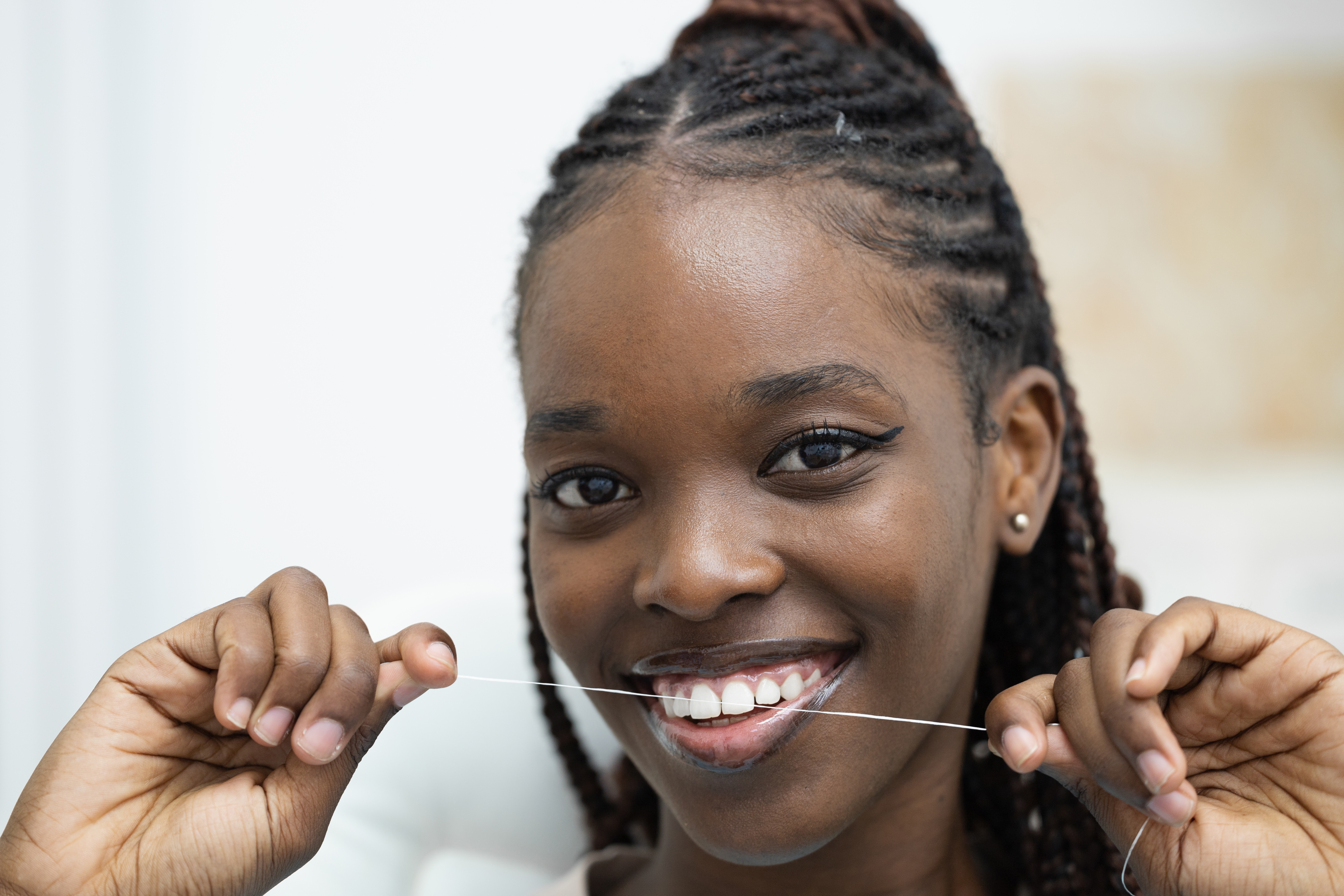 Person som smiler mens han bruker tanntråd, poserer i et nærbilde, viser munnhygiene
