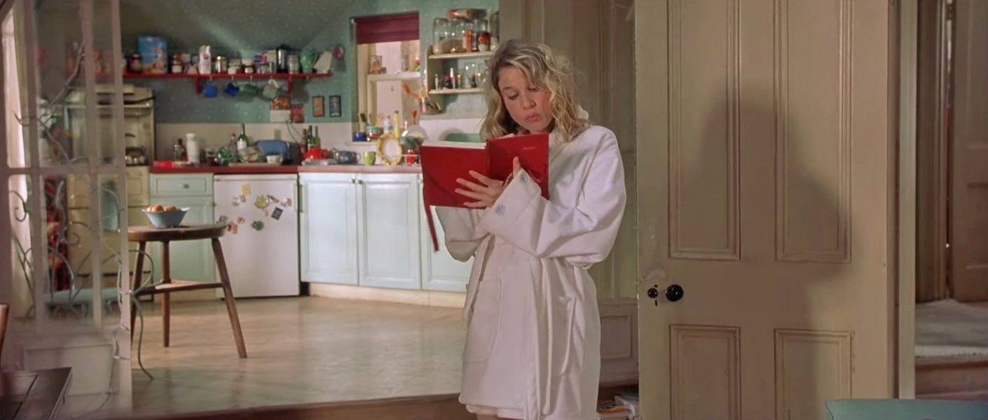 Person successful  a achromatic  robe reads a reddish  publication  successful  a cozy room  with unfastened  shelves and assorted  items visible