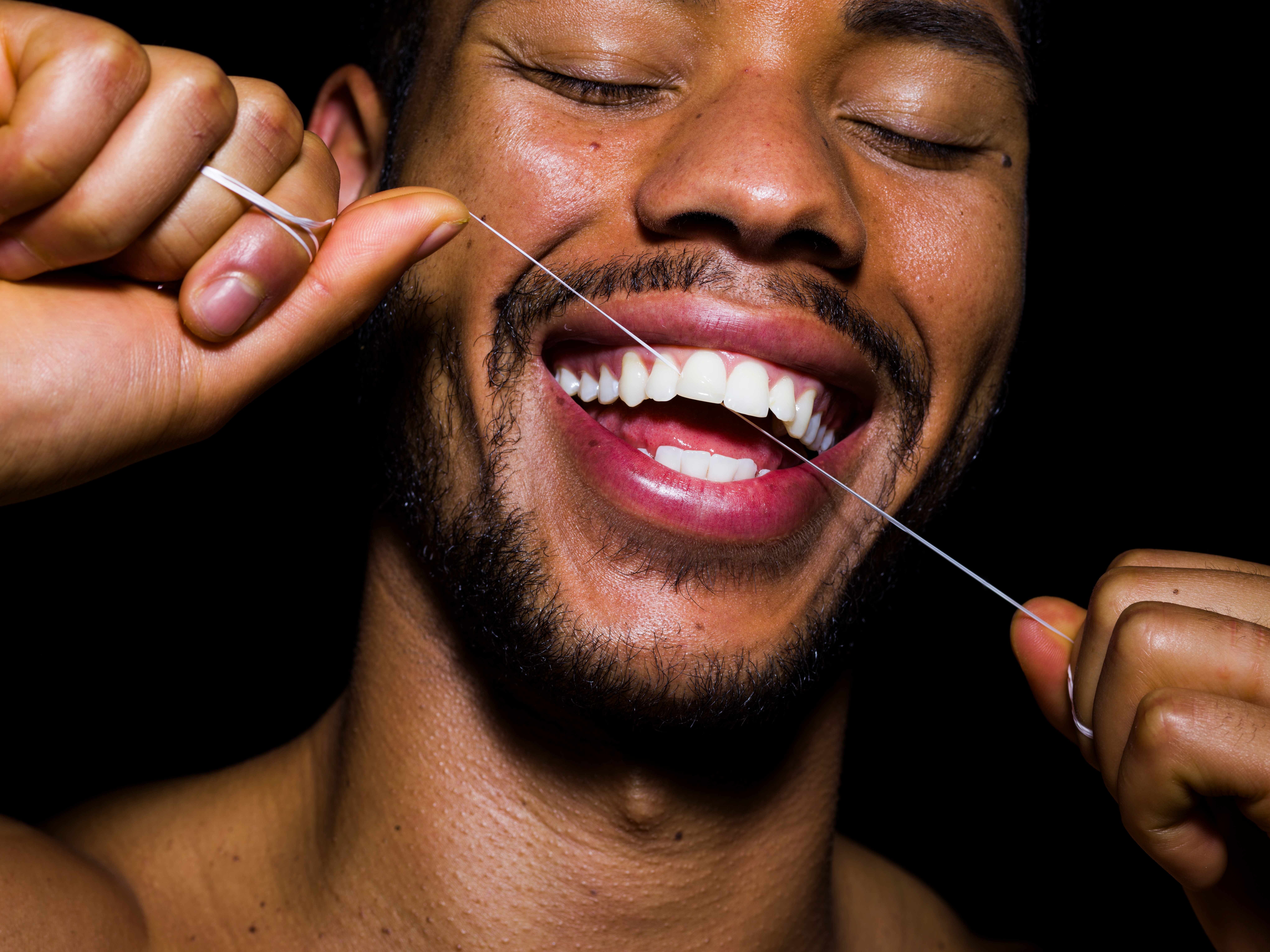 Person som smiler bredt mens han bruker tanntråd