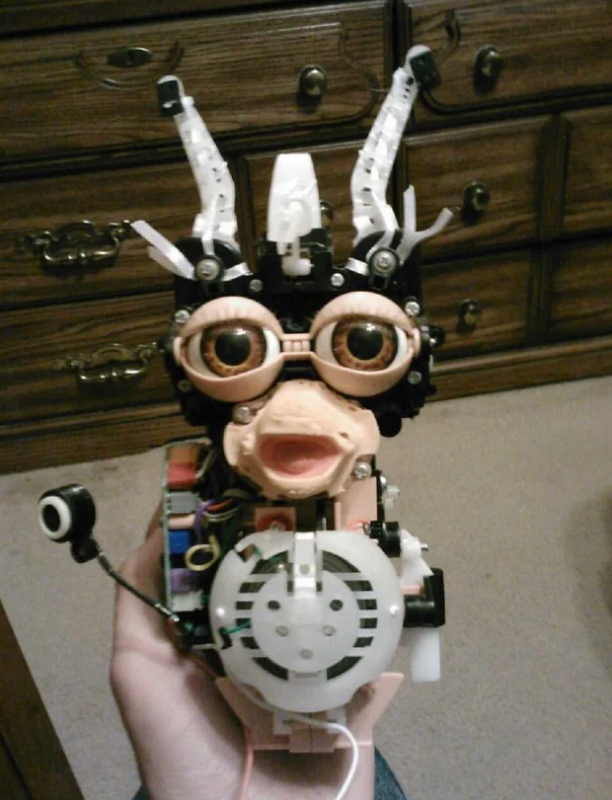 Robot-like Furby artifact  caput  with exposed mechanical parts and ample  eyes
