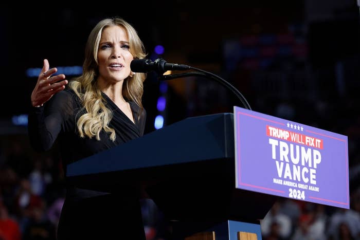 Person in a black outfit speaks passionately at a podium displaying &quot;Trump Vance 2024.&quot;