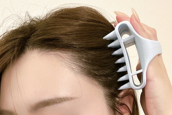 女性がシリコン製の頭皮マッサージャーを使用している様子。