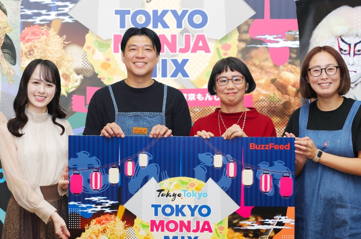 4人のグループが「TOKYO MONJA MIX」と書かれたサインを持っている。背景には伝統的な日本のアートが飾られている。