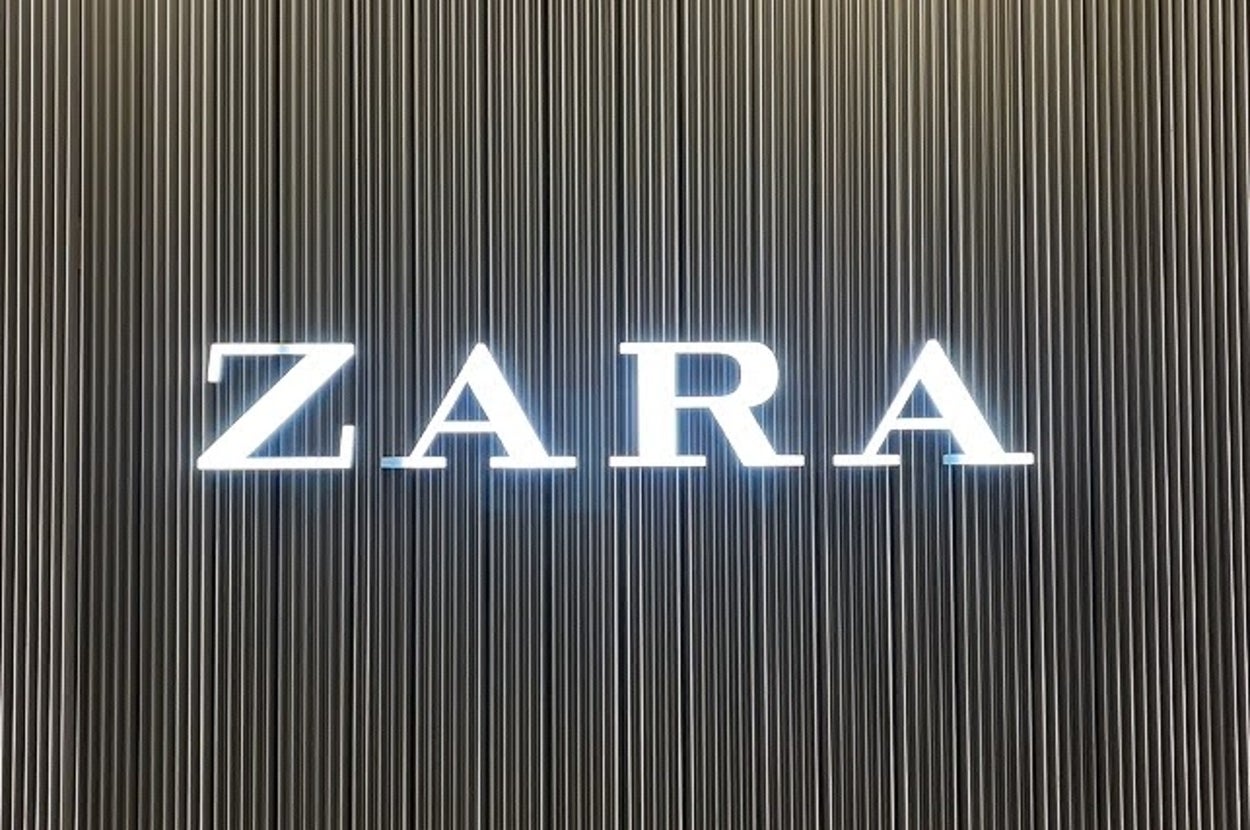 Zara store entrance with illuminated logo on a striped wall, showcasing the brand's elegant and modern aesthetic