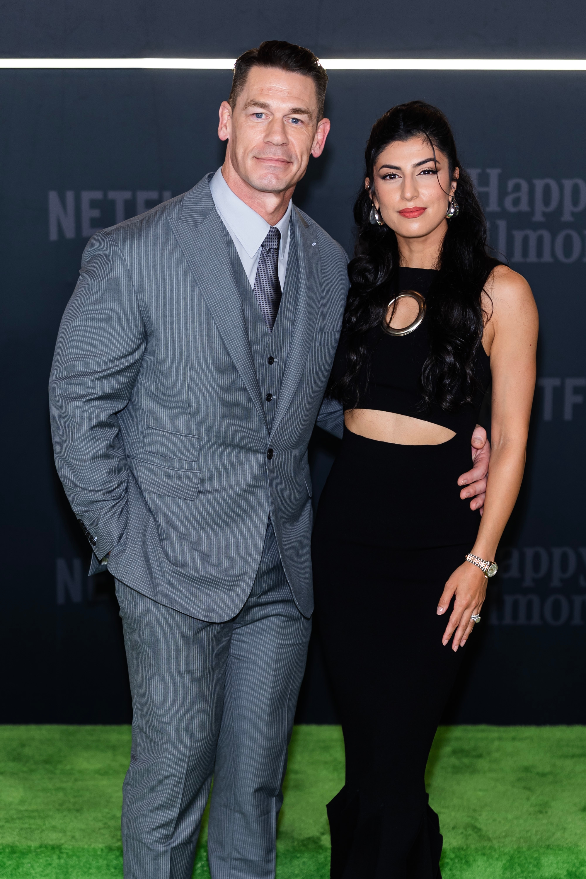 A antheral successful a grey suit and a pistillate successful a stylish achromatic formal airs unneurotic connected a greenish carpet astatine a personage event