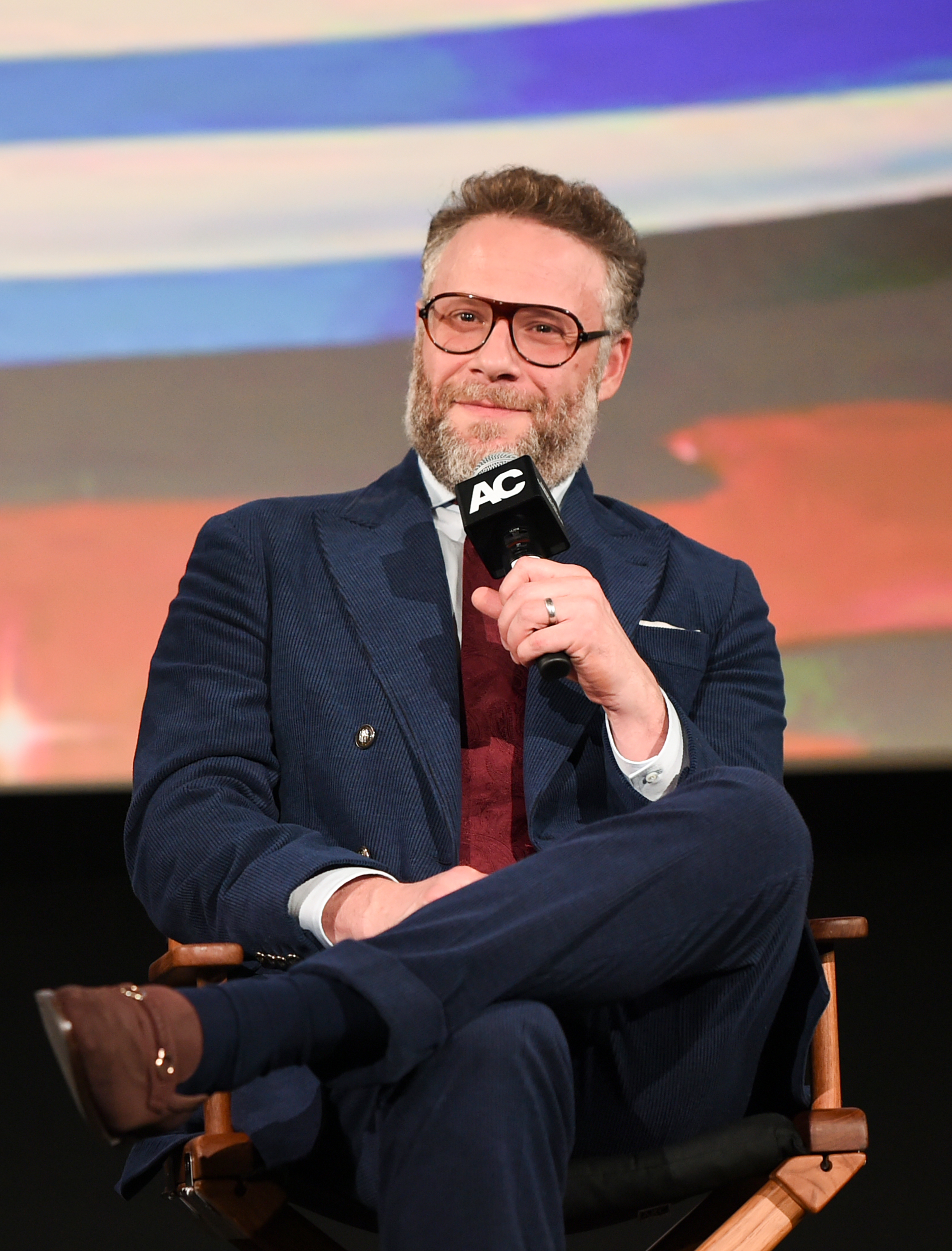 Man successful a bluish suit and reddish necktie holding a microphone, seated connected signifier during a nationalist event