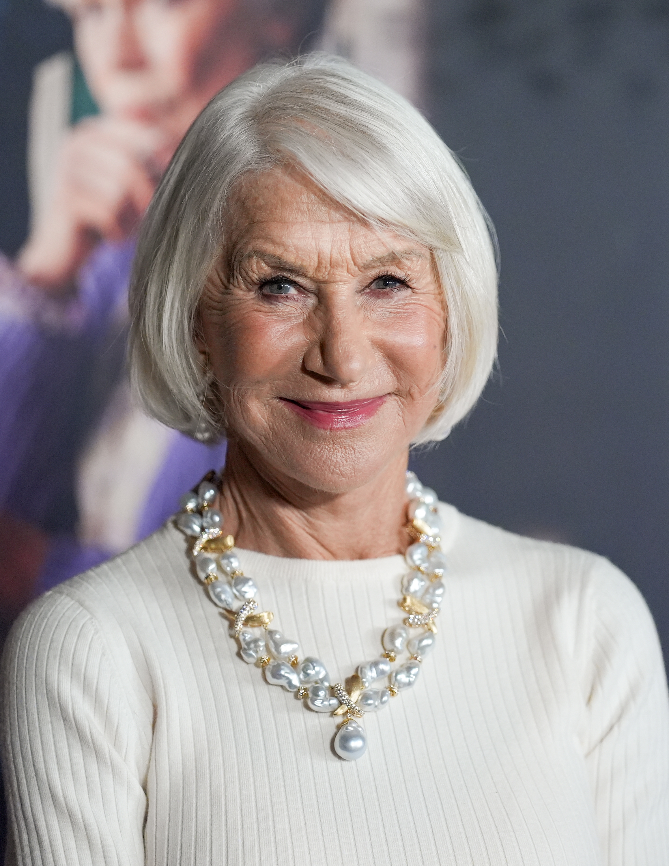 Person successful elegant achromatic sweater with a pearl necklace, smiling astatine a ceremonial event