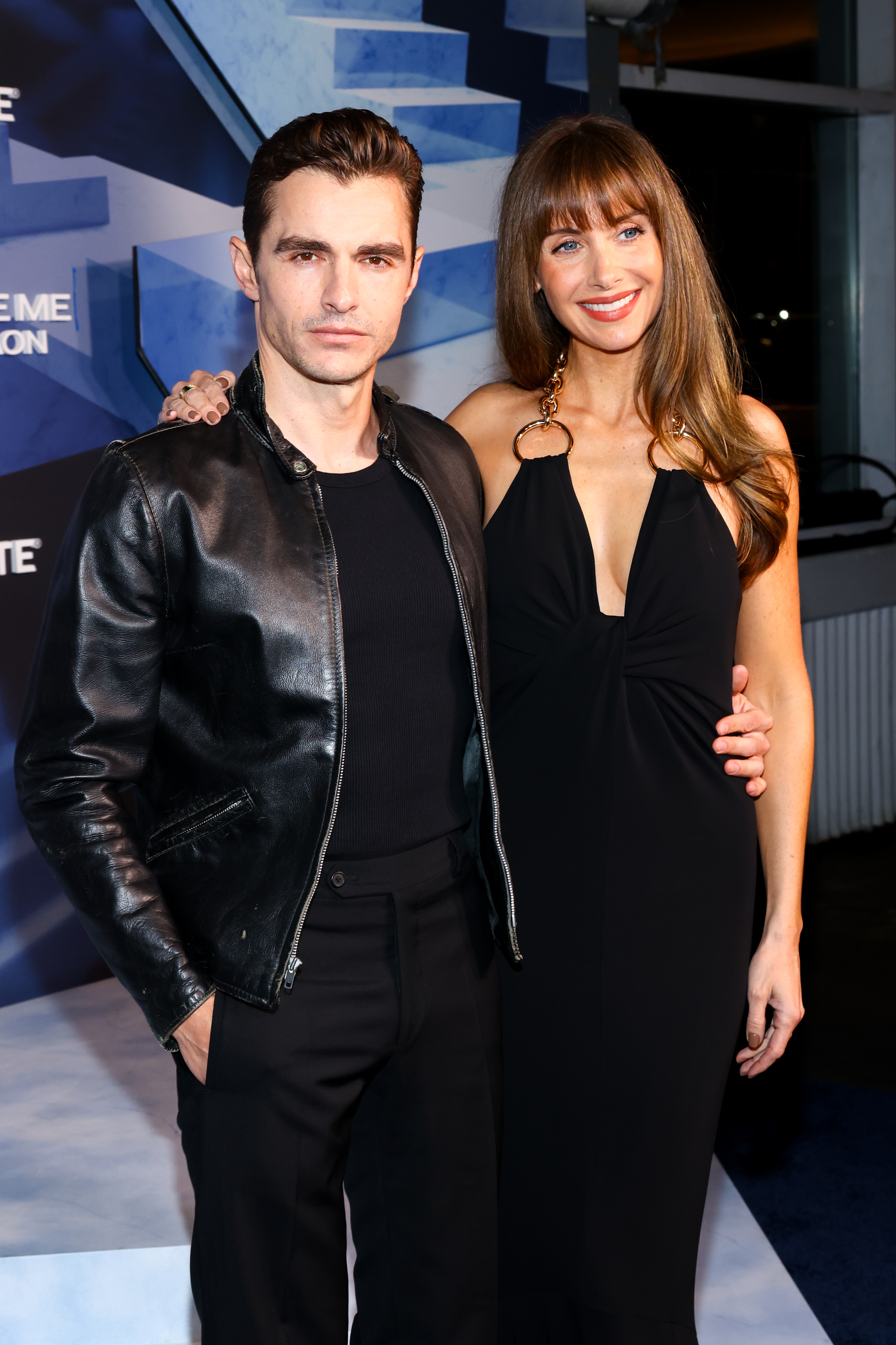 A antheral successful a leather overgarment and a pistillate successful a halter-neck gown airs unneurotic connected an lawsuit backdrop