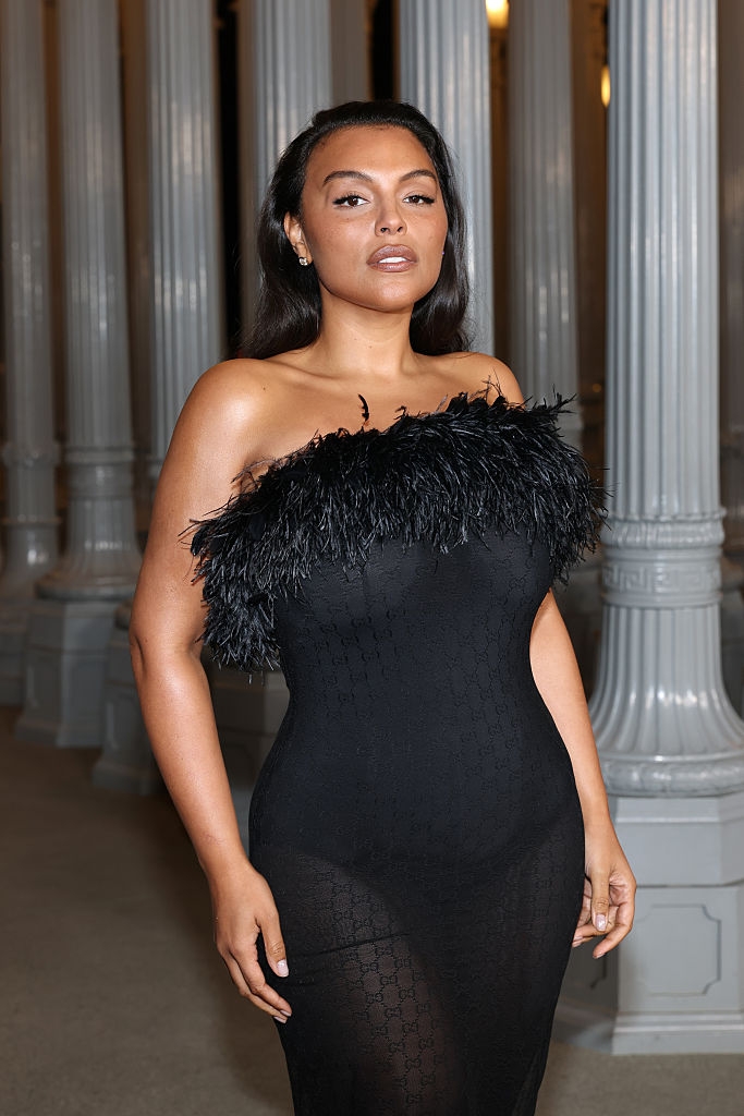 Person successful elegant, form-fitting achromatic formal with feathered neckline stands confidently successful beforehand of architectural columns