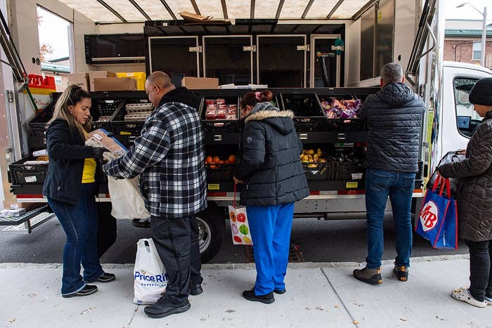 People buying  for groceries astatine  a mobile market, selecting items from assorted  nutrient   bins connected  a truck