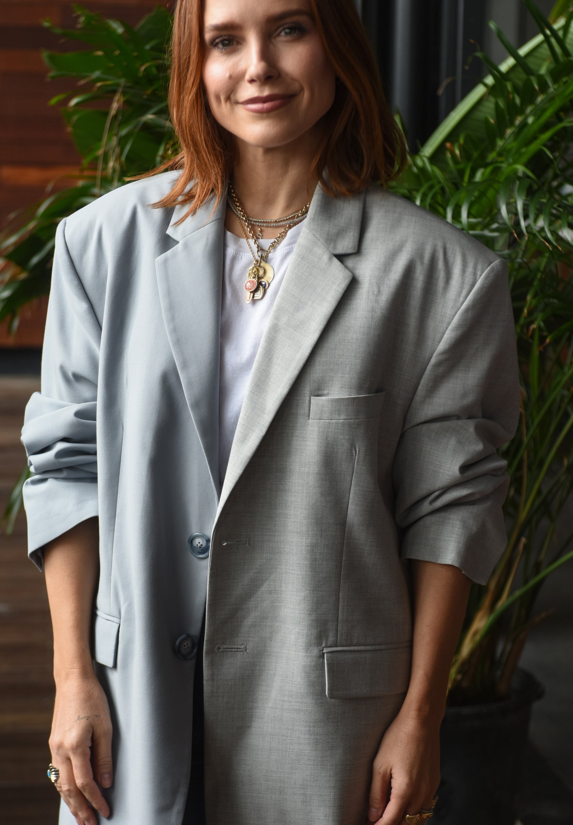 Person successful  an oversized blazer with rolled sleeves, layered necklaces, and casual jeans, lasting  indoors