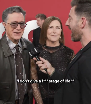 A man in a leather jacket and woman in a glittery dress are interviewed on a red carpet. Visible text: &quot;I don&#x27;t give a f*** stage of life.&quot;