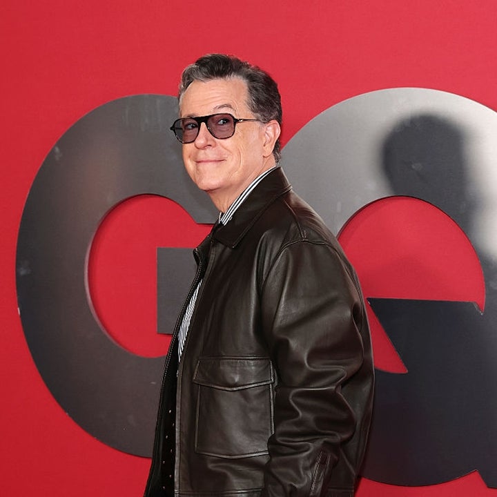 Person on red carpet in leather jacket and striped shirt, posing in front of large decorative letters