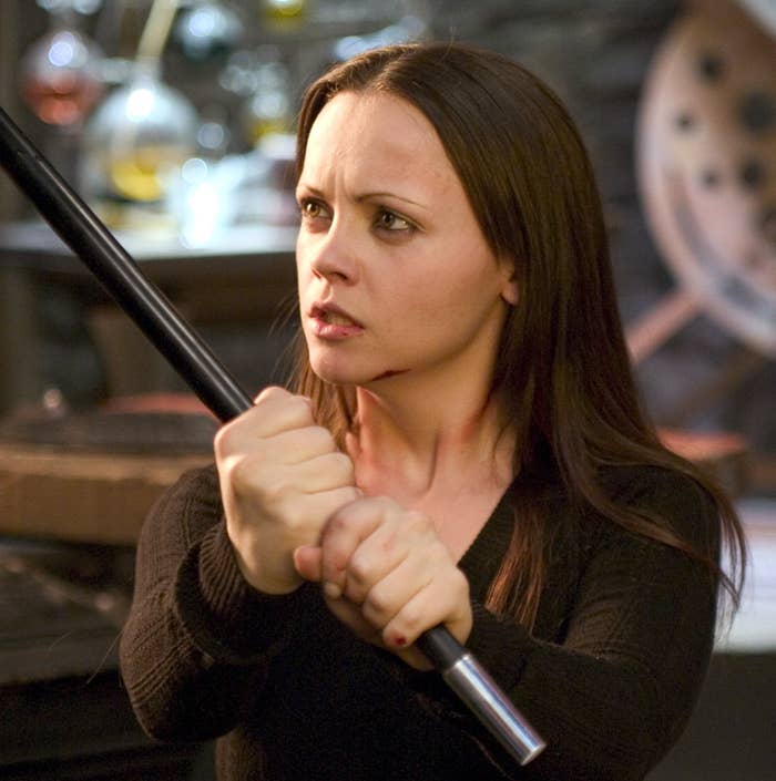 Person holding a long object defensively, in a dramatic scene setting with focus on intense expression