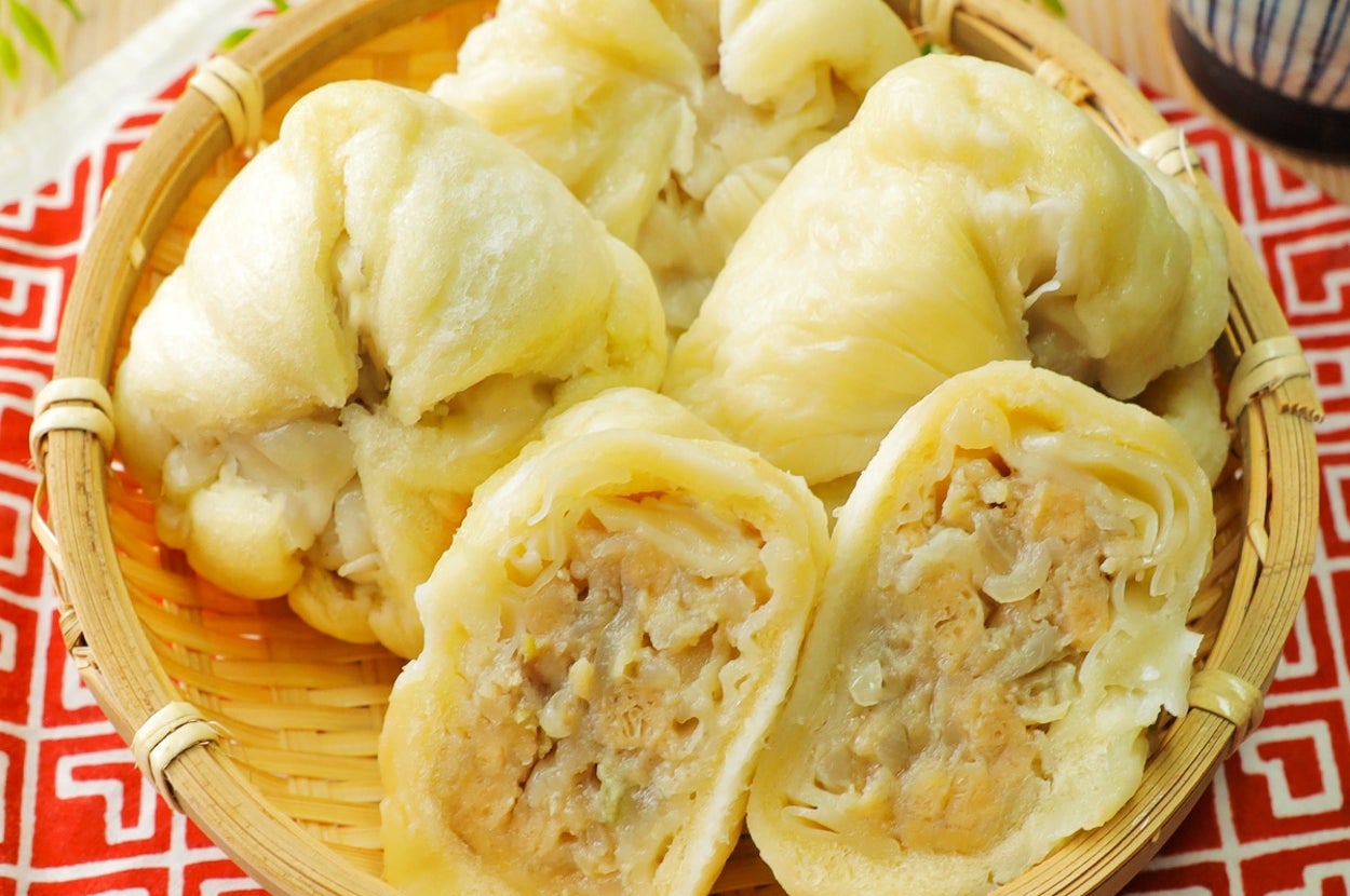 蒸した中華まんが竹かごに盛られている。半分に切られたものもあり、中身が見える。