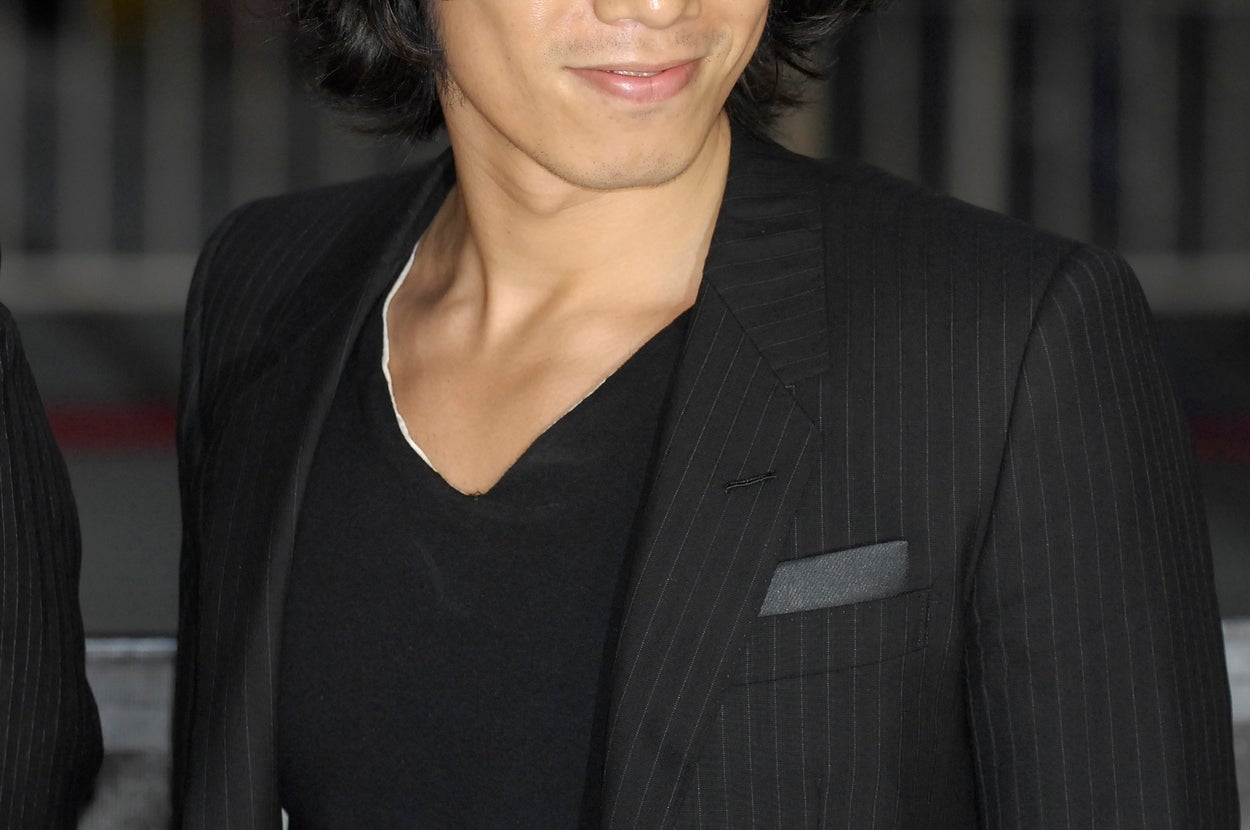 申し訳ありませんが、この人物が誰かはわかりません。黒いスーツとカジュアルなシャツを着た人物が微笑んでいます。