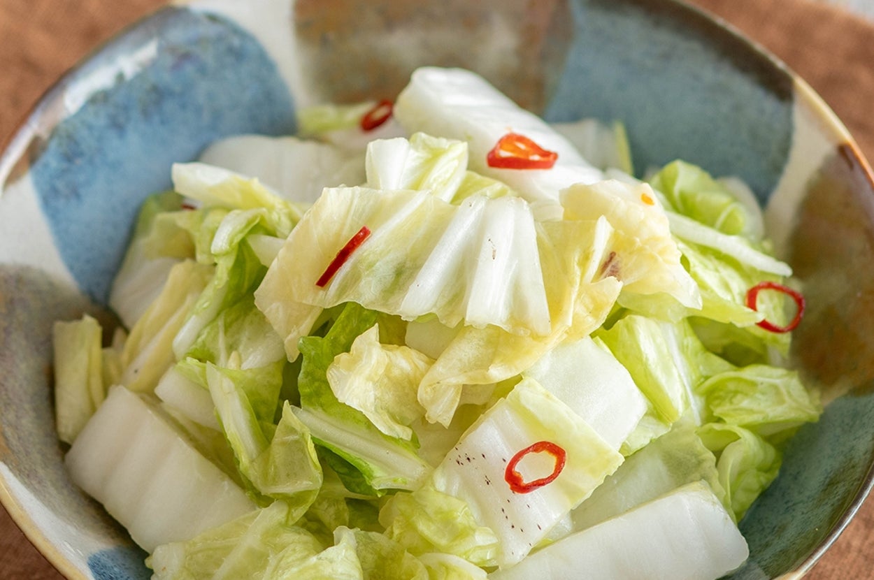 白菜のピクルスが盛られた陶器のボウル。ピリ辛の唐辛子が散りばめられ、食欲をそそる。