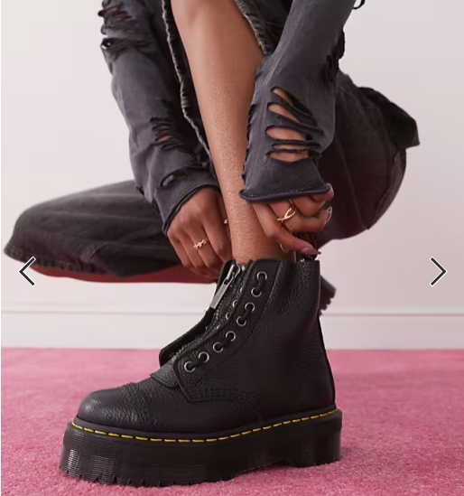 Person successful ripped jeans adjusts a chunky, achromatic combat footwear connected a carpeted floor