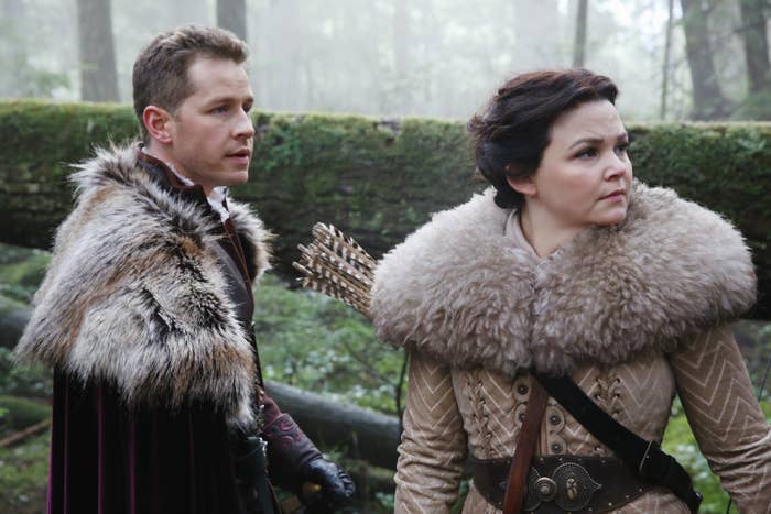 Two radical   successful  phantasy  attire with fur-trimmed coats basal   successful  a misty forest, looking intently to the right. One has arrows connected  their back