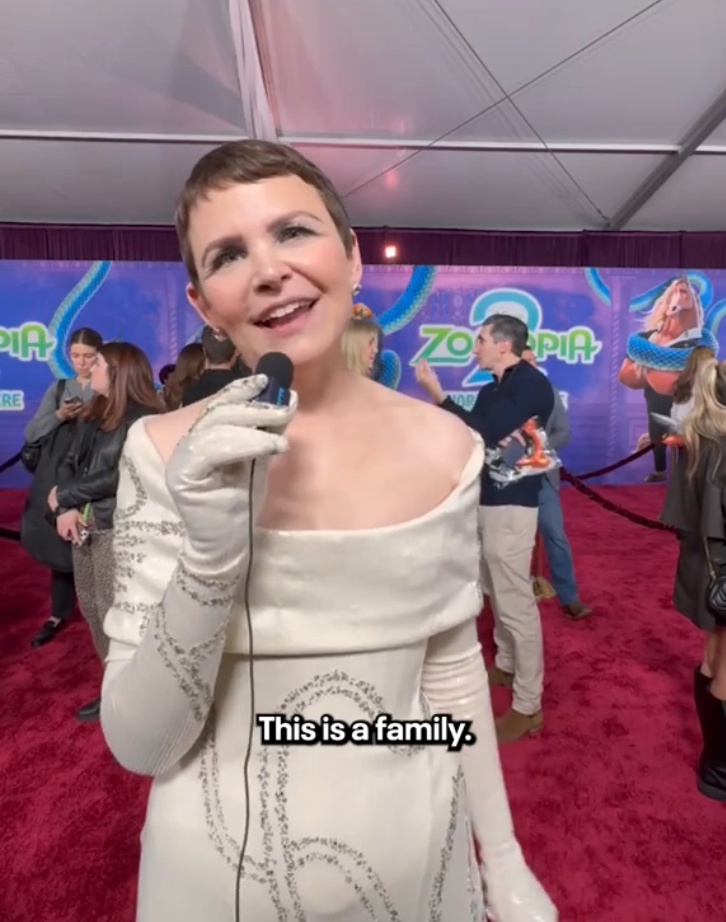 Person successful off-white, off-shoulder formal with sequins holding a microphone connected a reddish carpet; substance reads, "This is simply a family."