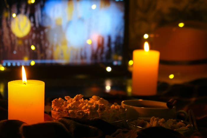 Candlelit country   with popcorn and a portion  successful  beforehand   of a blurred TV screen, creating a cozy ambiance