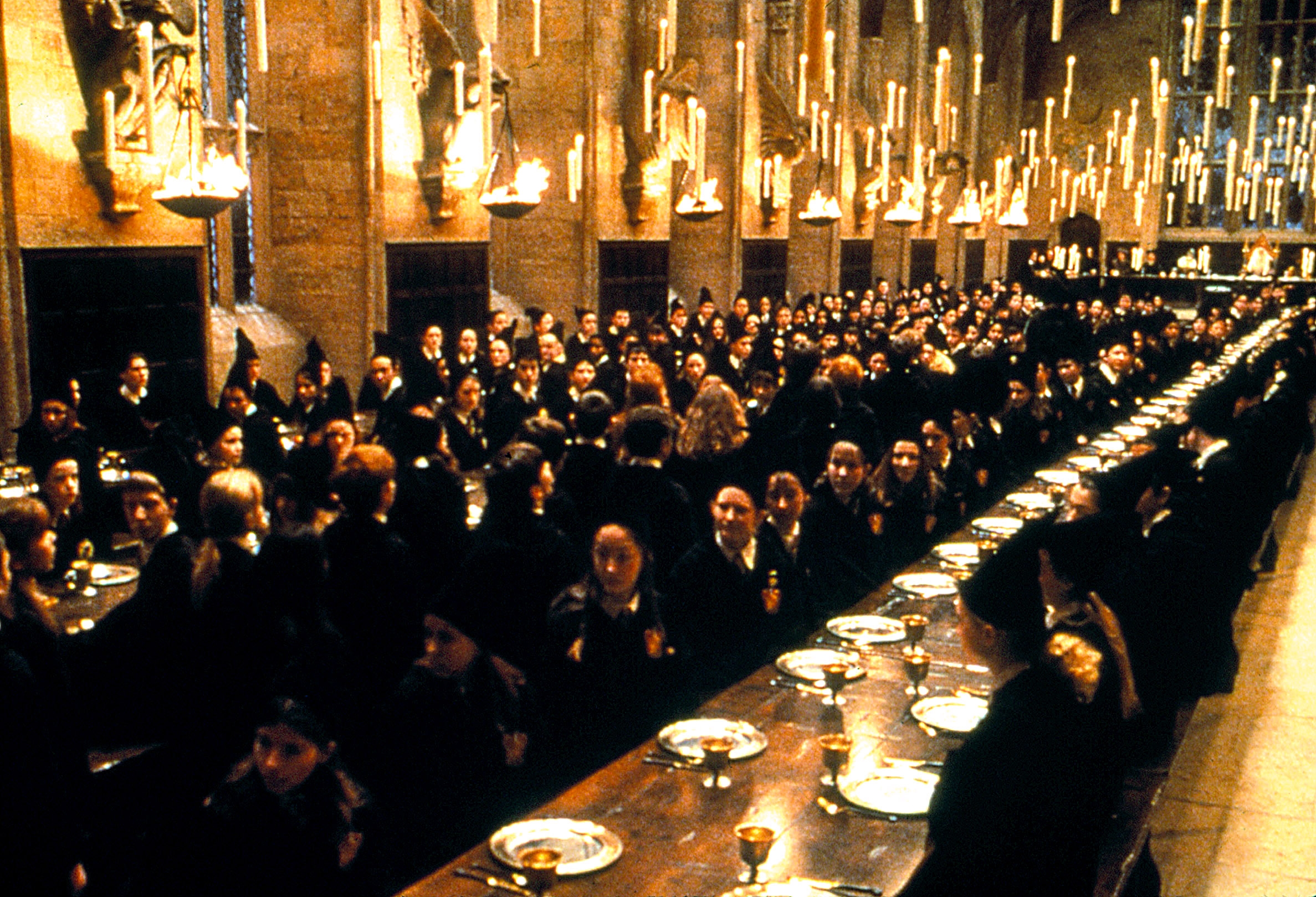 Large hallway  with agelong  tables filled with students successful  robes and pointed hats, resembling a schoolhouse  eating  mounting  from a phantasy  movie