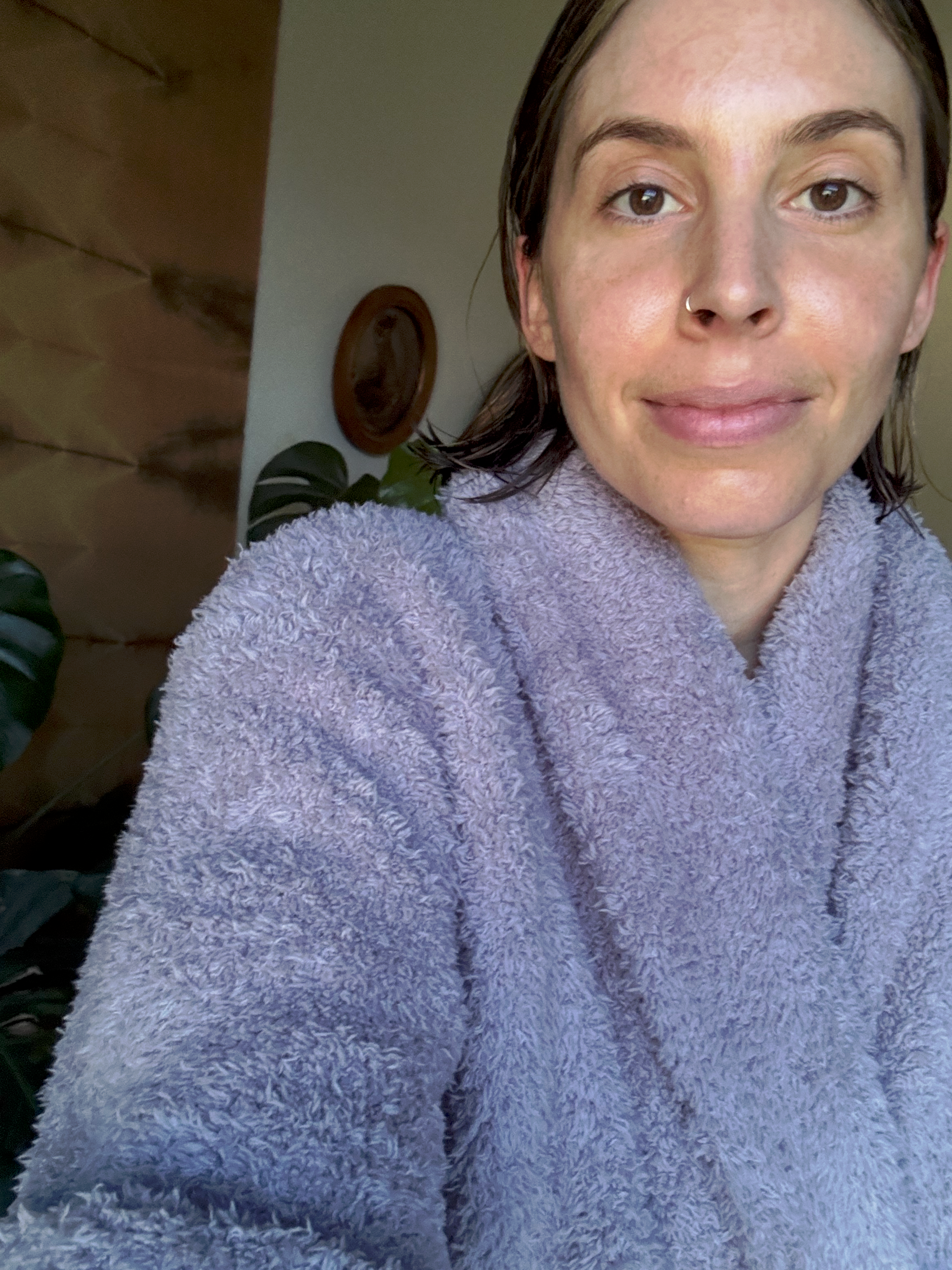 Person som har på seg en myk Barefoot Dreams CozyChic Robe, ser avslappet ut, med planter i bakgrunnen