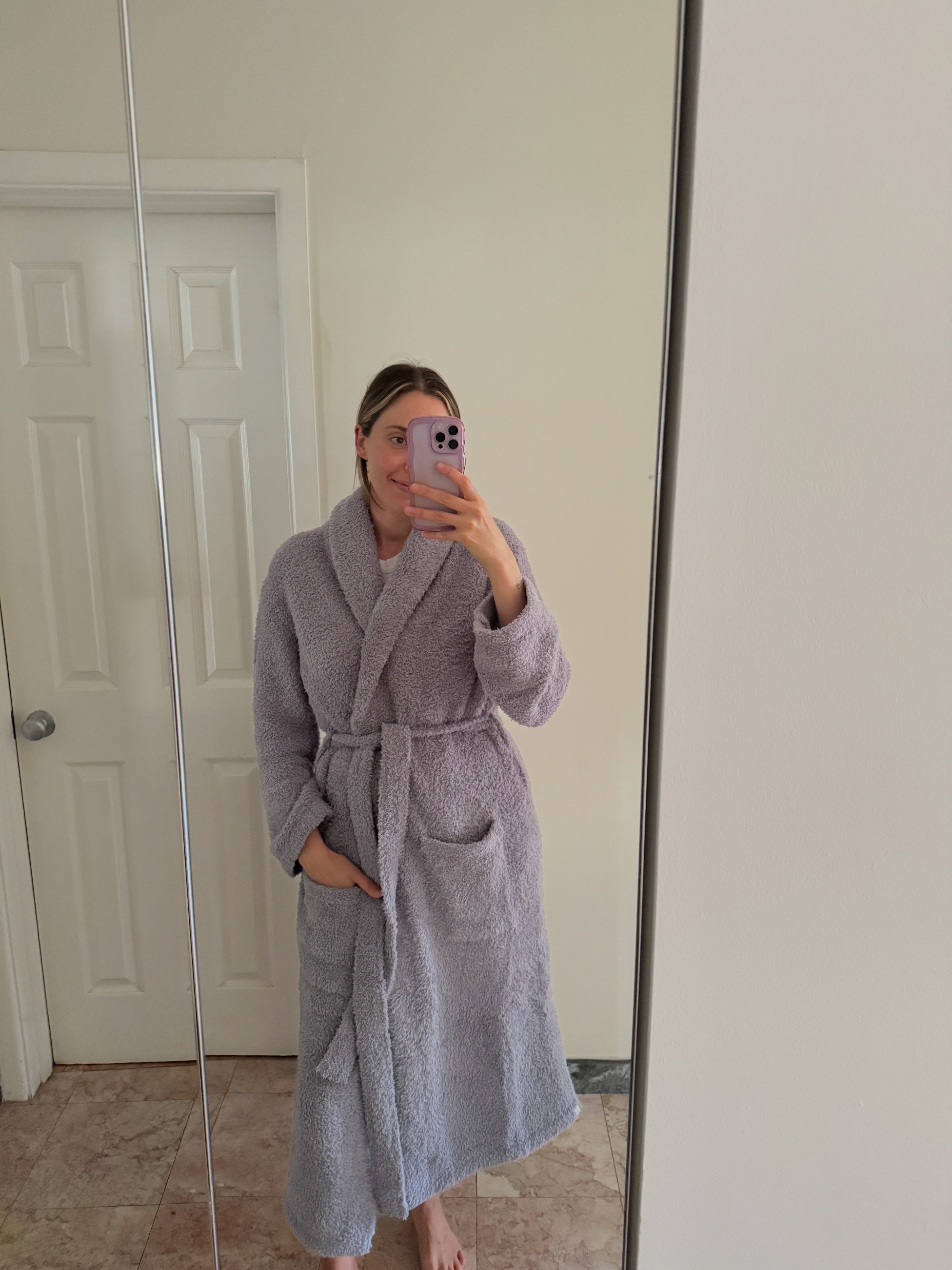 Person i en koselig, myk Barefoot Dreams CozyChic Robe, smilende mens han tar en speilselfie på et bad