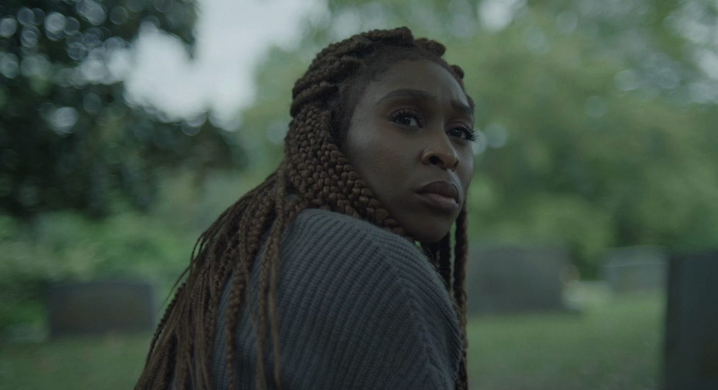 Woman with braided hairsbreadth  successful  a thoughtful pose, wearing a textured sweater outdoors with a blurred, greenish  background