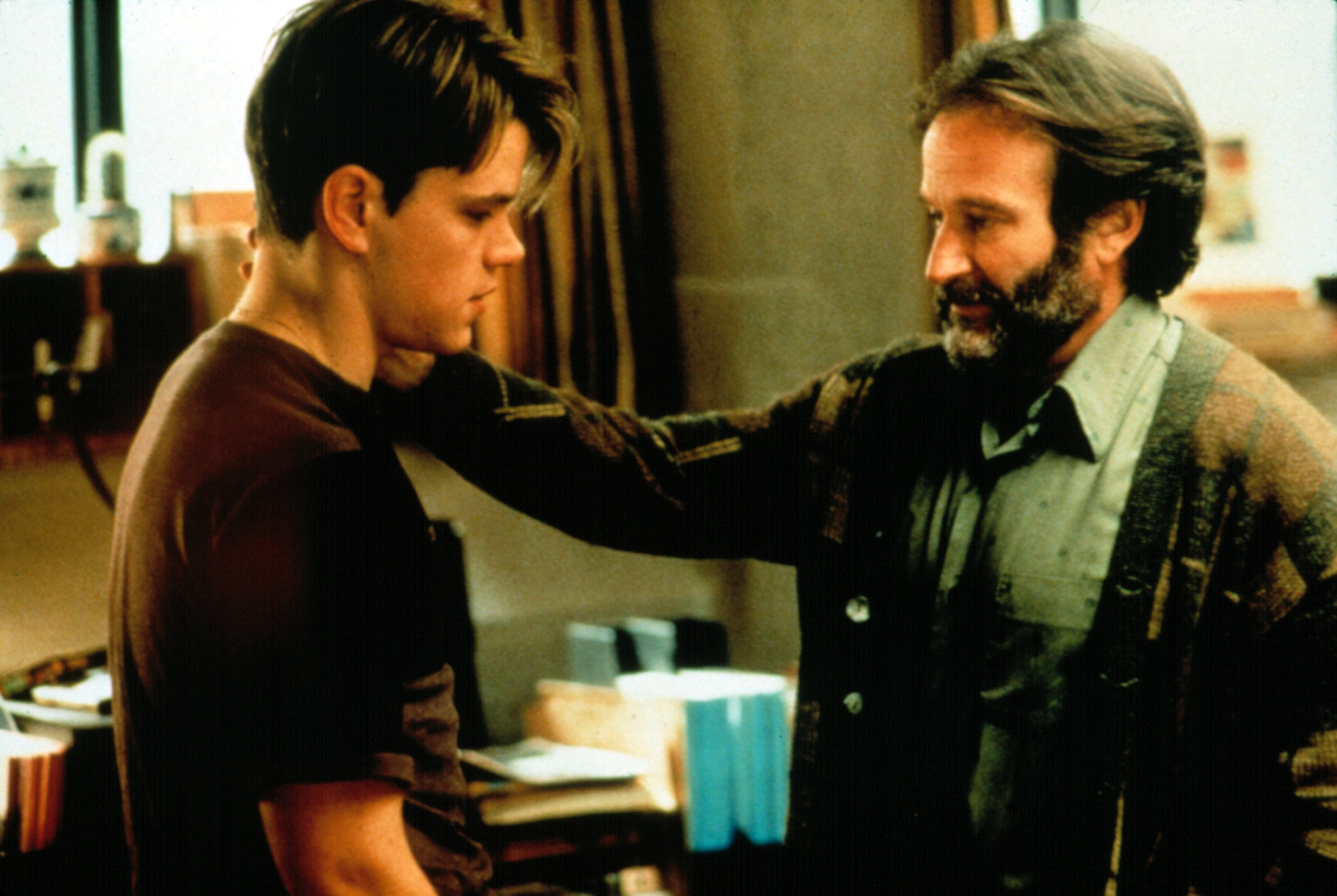 To personer i en alvorlig samtale, den ene med uformelle klær og den andre med en cardigan, i et varmt opplyst rom