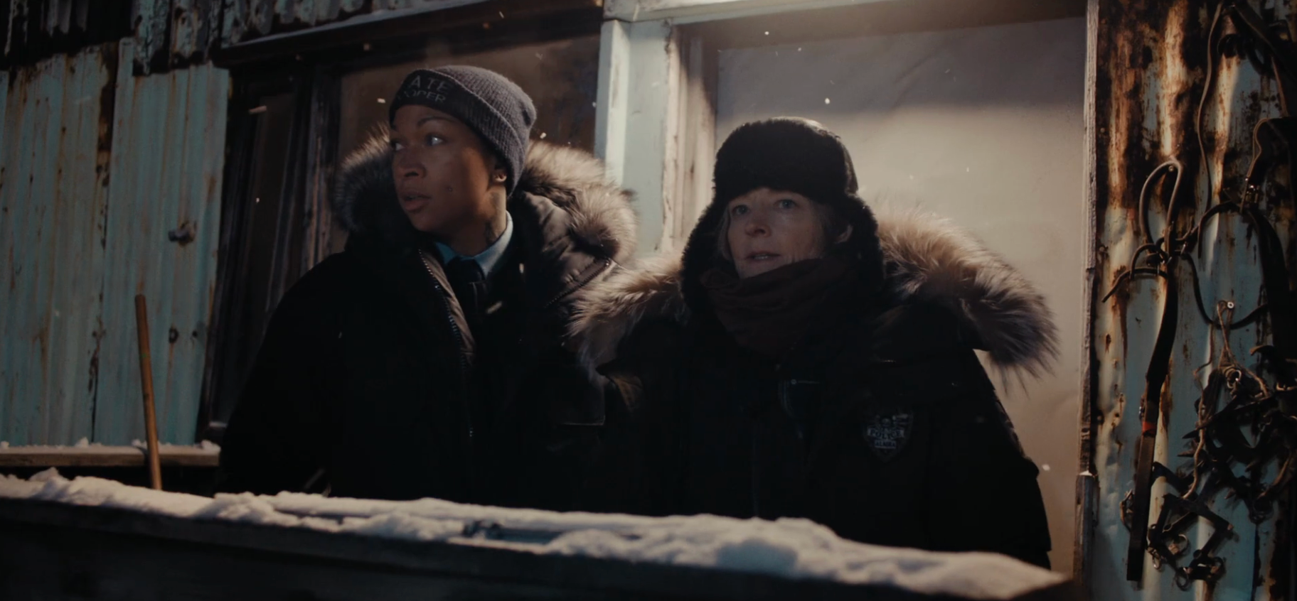 Two radical   successful  fur-trimmed coats basal   extracurricular  a snowy building, looking into the distance, conveying a serious, contemplative mood
