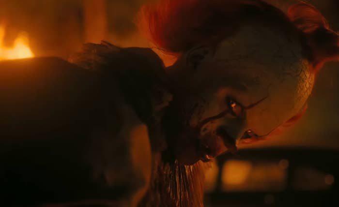 Creepy clown with crisp  teeth and messy reddish  hair, leaning with a menacing look  successful  a dimly lit country   from a fearfulness   movie