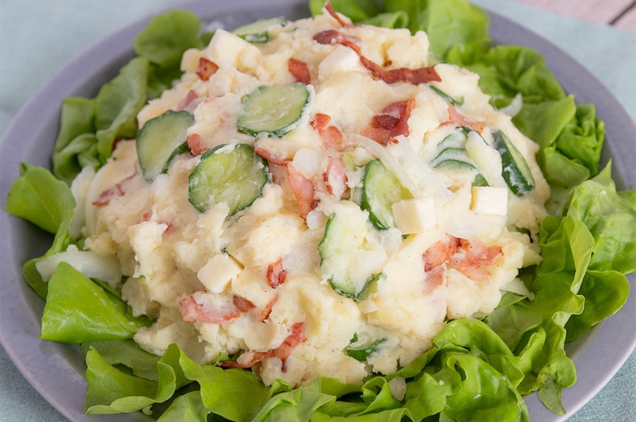皿に盛られたポテトサラダのアップ。スライスされたきゅうり、ベーコン、レタスがトッピングされている。