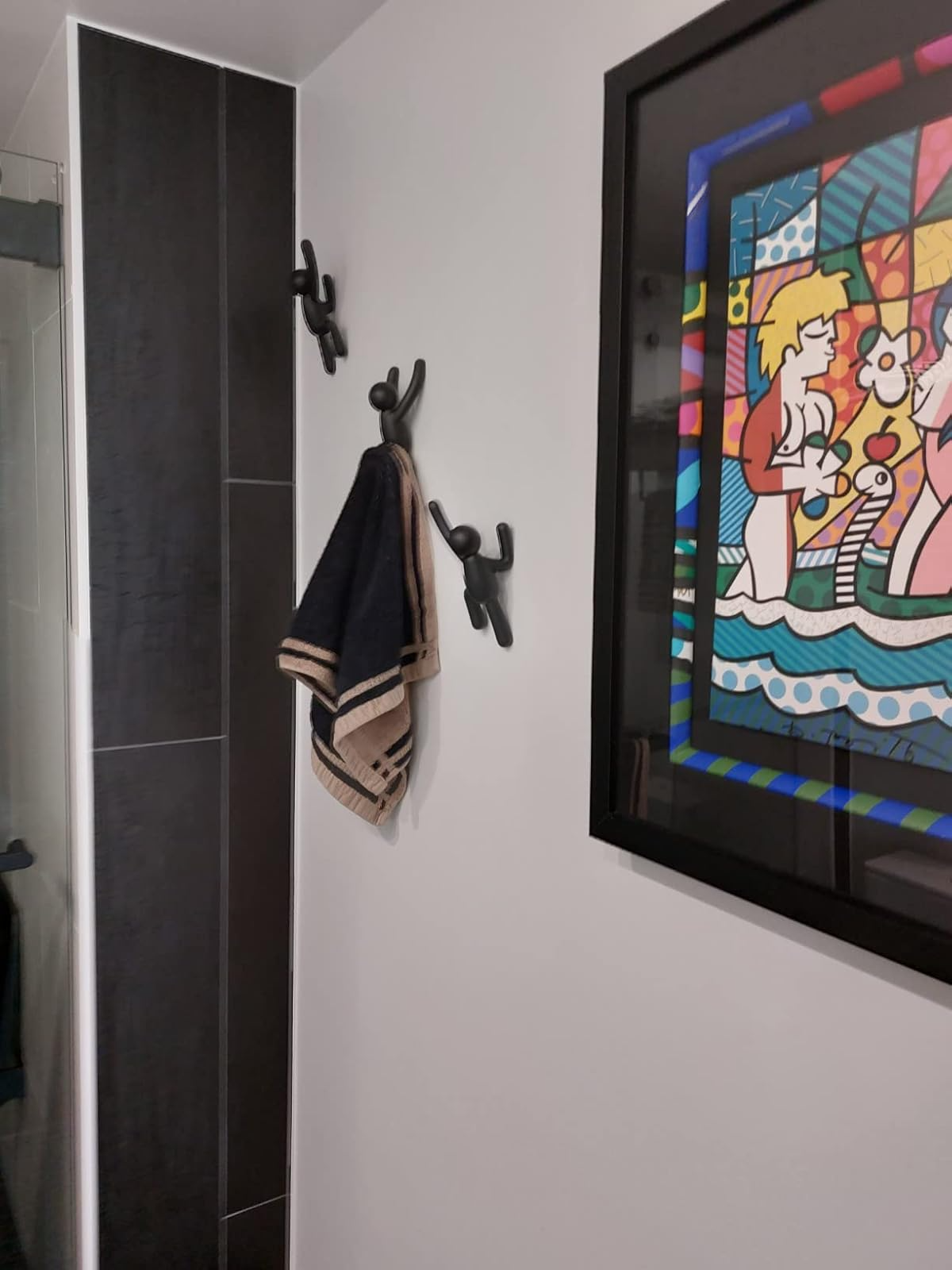 Bathroom partition  with 2  towel hooks holding a towel and framed cartoon-style creation  of children with flowers