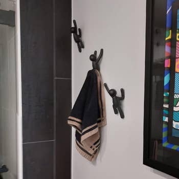 Bathroom partition with 2 towel hooks holding a towel and framed cartoon-style creation of children with flowers