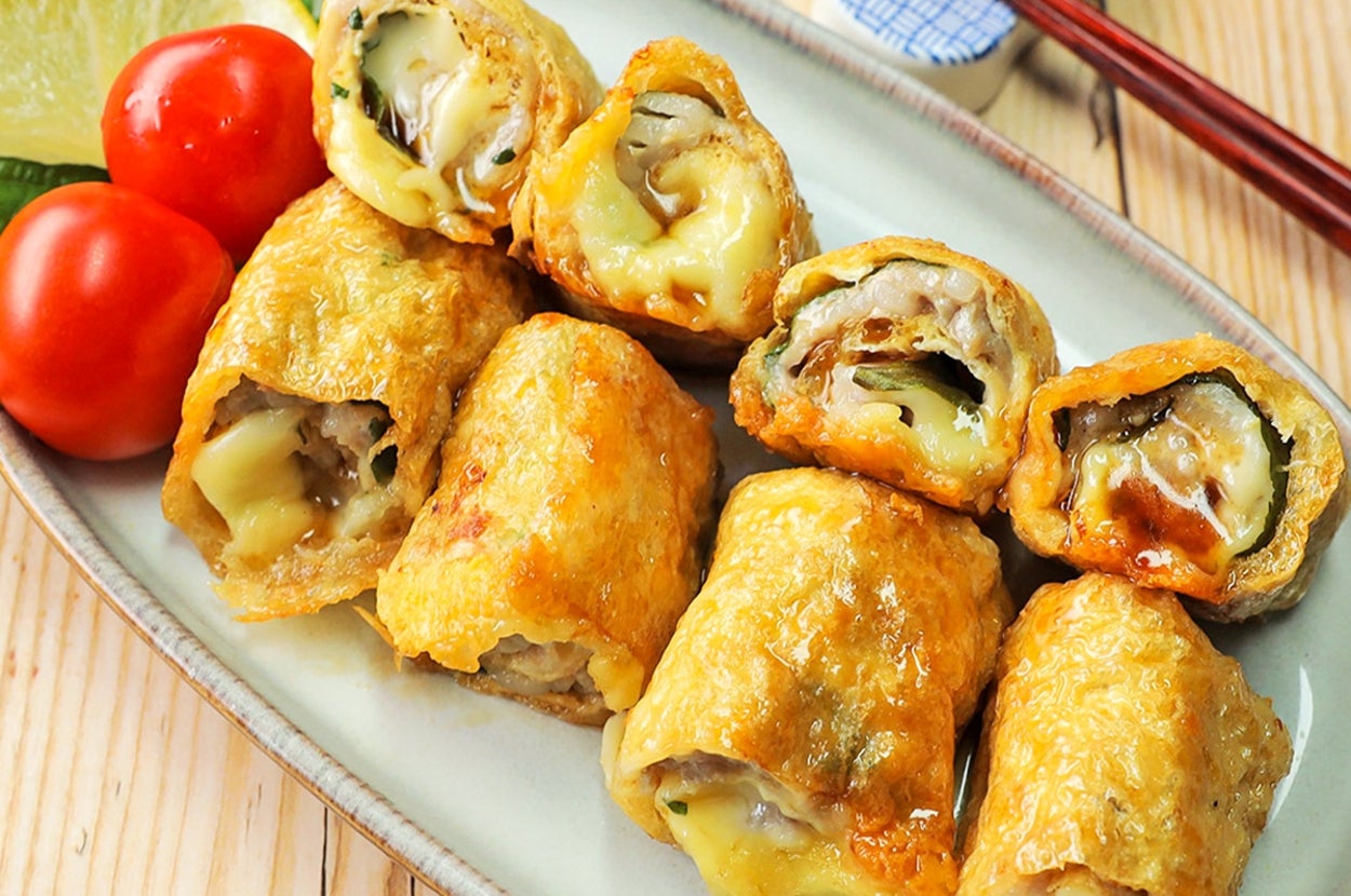 お皿に盛られた揚げた春巻きとミニトマト、レモンのスライス、箸が添えられた食事の写真。