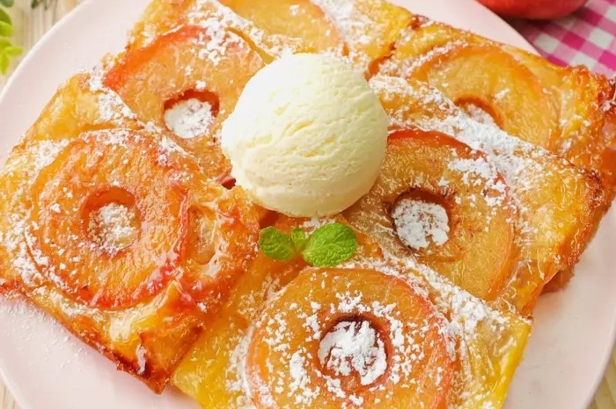 リンゴのスライスをのせたパイ生地にアイスクリームが添えられたデザート。粉砂糖が振りかけられている。