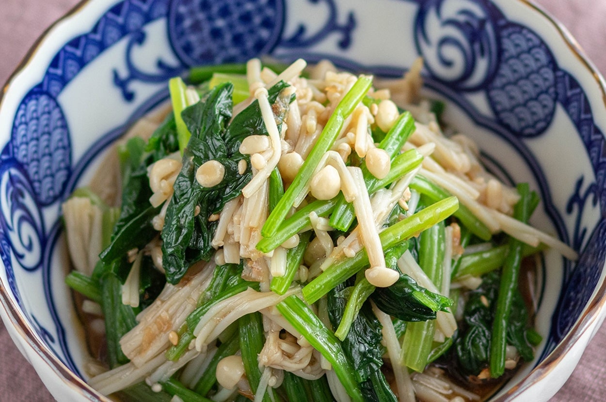 ボウルに盛られたほうれん草とえのきの和え物。料理は伝統的な陶器に盛られ、美しく盛り付けられている。