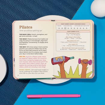 Open publication astir Pilates exercises connected a patterned surface, with a pinkish pen beside it. A cartoon shows a idiosyncratic lifting vino bottles arsenic weights