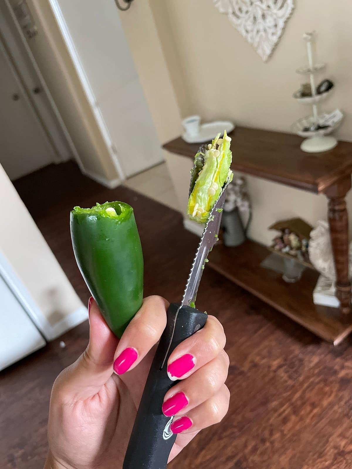 Person holding a jalapeño capsicum  with a corer, showcasing an casual  room  instrumentality   for capsicum  preparation