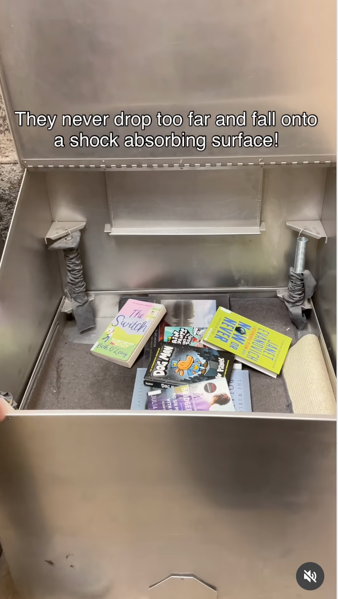 Open metallic  container  with daze  absorbers, containing books including &quot;The Switch&quot; and &quot;The Martian.&quot; Text supra  mentions books autumn  onto a cushioned surface