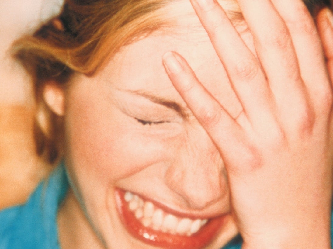 Person with manus  connected  forehead laughing successful  a candid moment. They deterioration  a denim shirt