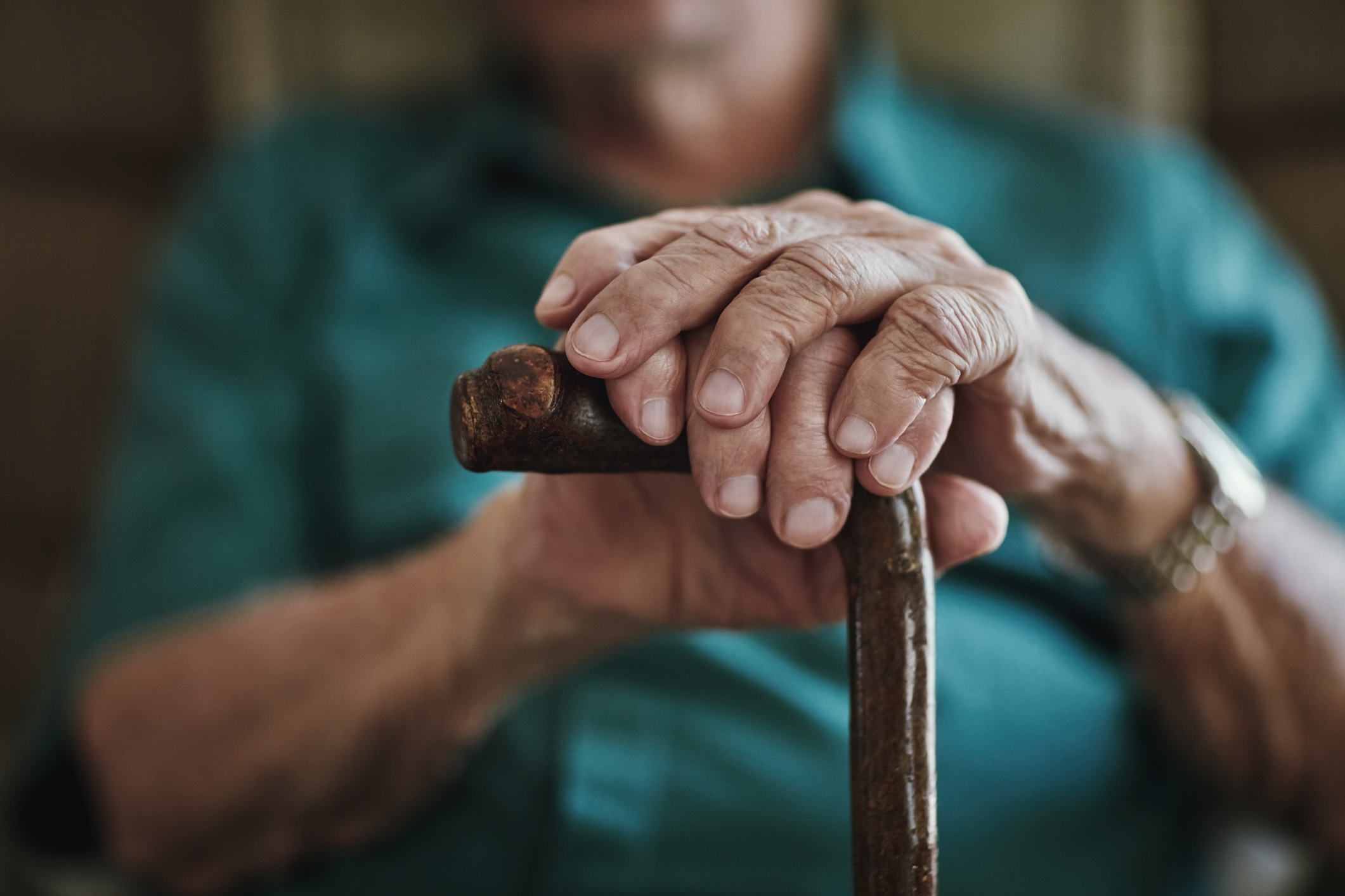 Elderly person&#x27;s hands resting connected  a woody  cane, conveying a consciousness   of property  and experience